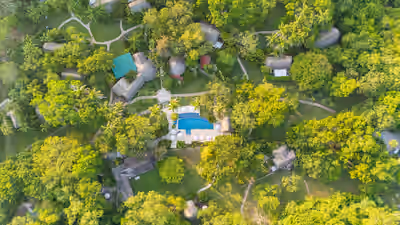 Aerial view of jungle eco‑resort with pool and network of thatched cottages at The Lodge at Chaa Creek, Belize