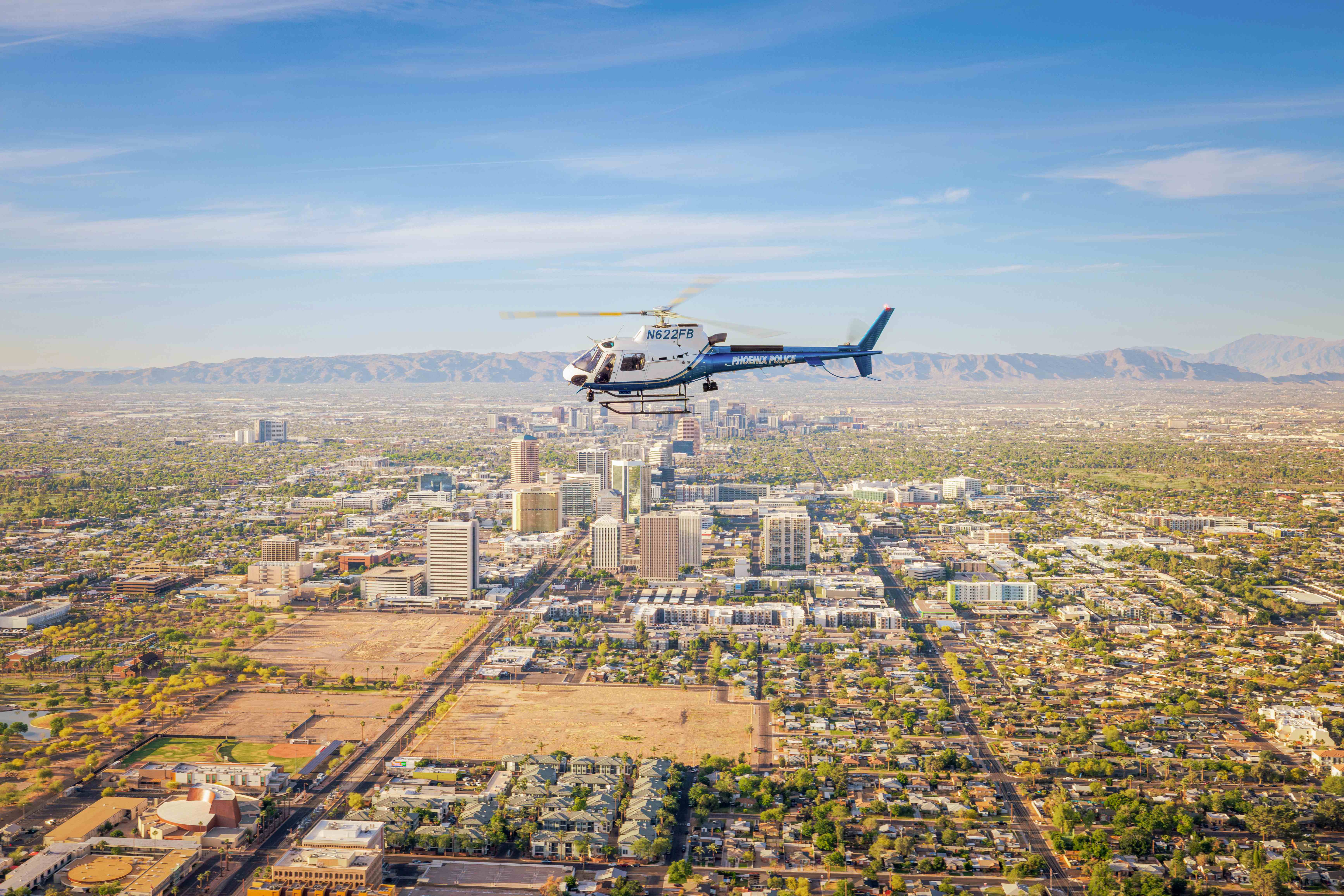 Phoenix Police Airbus H125 helicopter flying over downtown Phoenix with South Mountain in background
