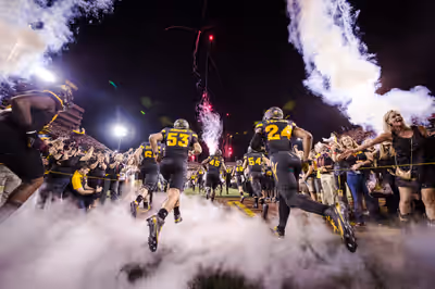 Arizona State football team entering field with smoke and fireworks, fans cheering in Tempe, AZ