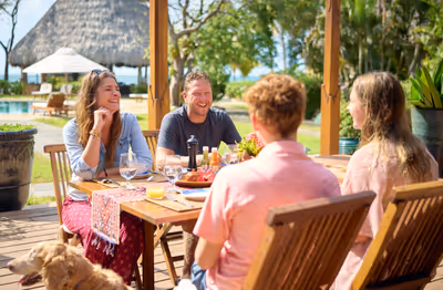 Family with kids enjoying breakfast together at outdoor resort table in Belize
