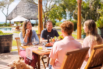 Family with kids enjoying breakfast together at outdoor resort table in Belize