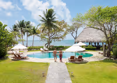 Couple walking toward beachfront pool at tropical resort in Belize