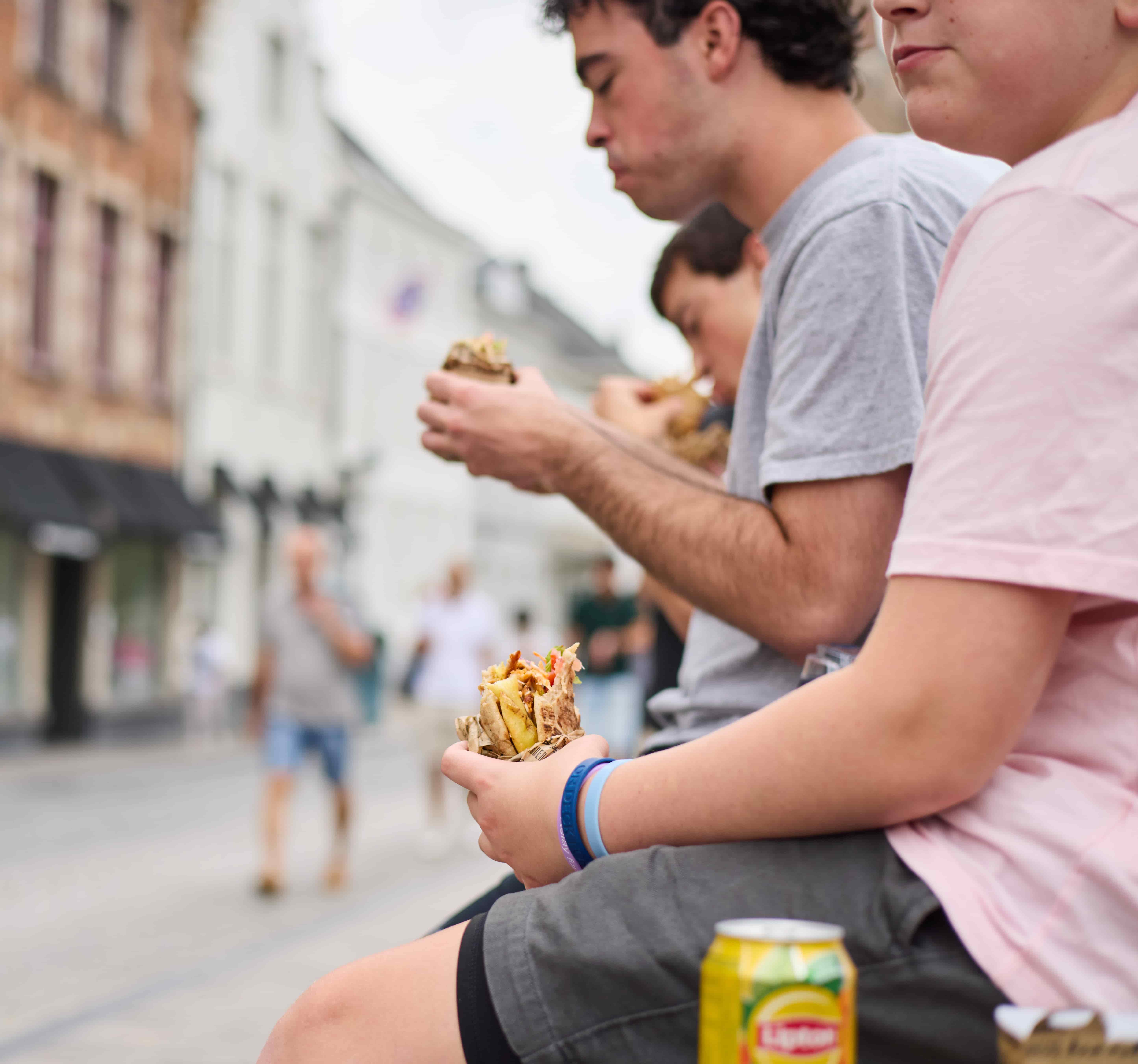 People eat sandwiches together beside a Bruges canal, Belgium People eating sandwiches together on a canal-side wall in Bruges