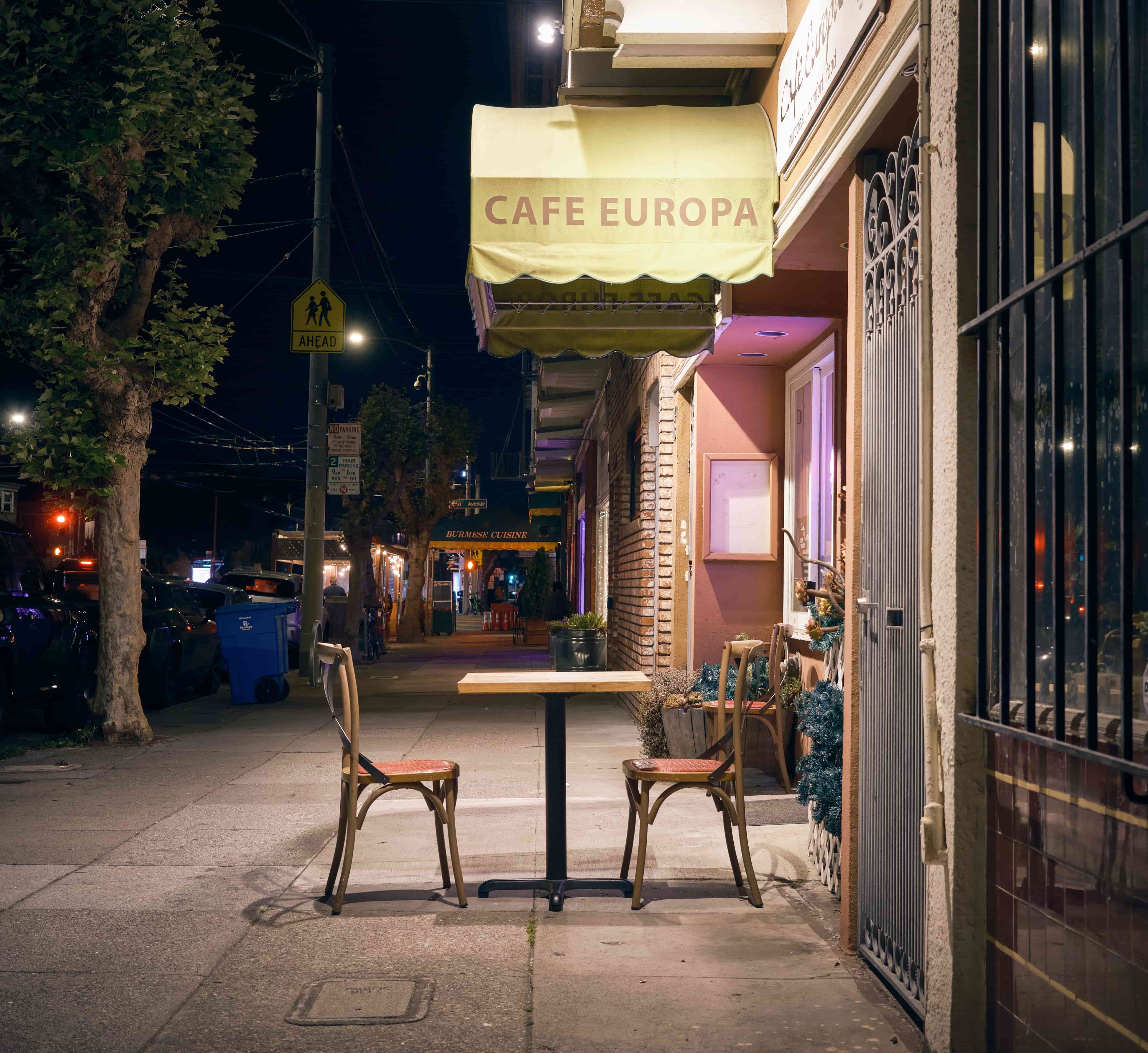 Empty cafe table at Cafe Europa at night, San Francisco, California Empty outdoor table and two chairs beneath Cafe Europa's lit awning at night