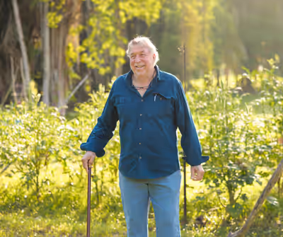 Older man smiling proudly in front of organic farm garden in Belize