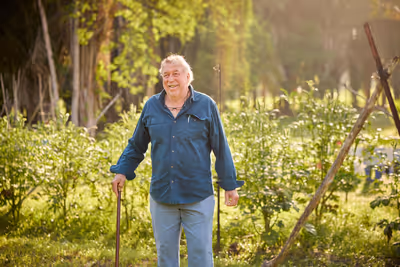 Older man smiling proudly in front of organic farm garden in Belize