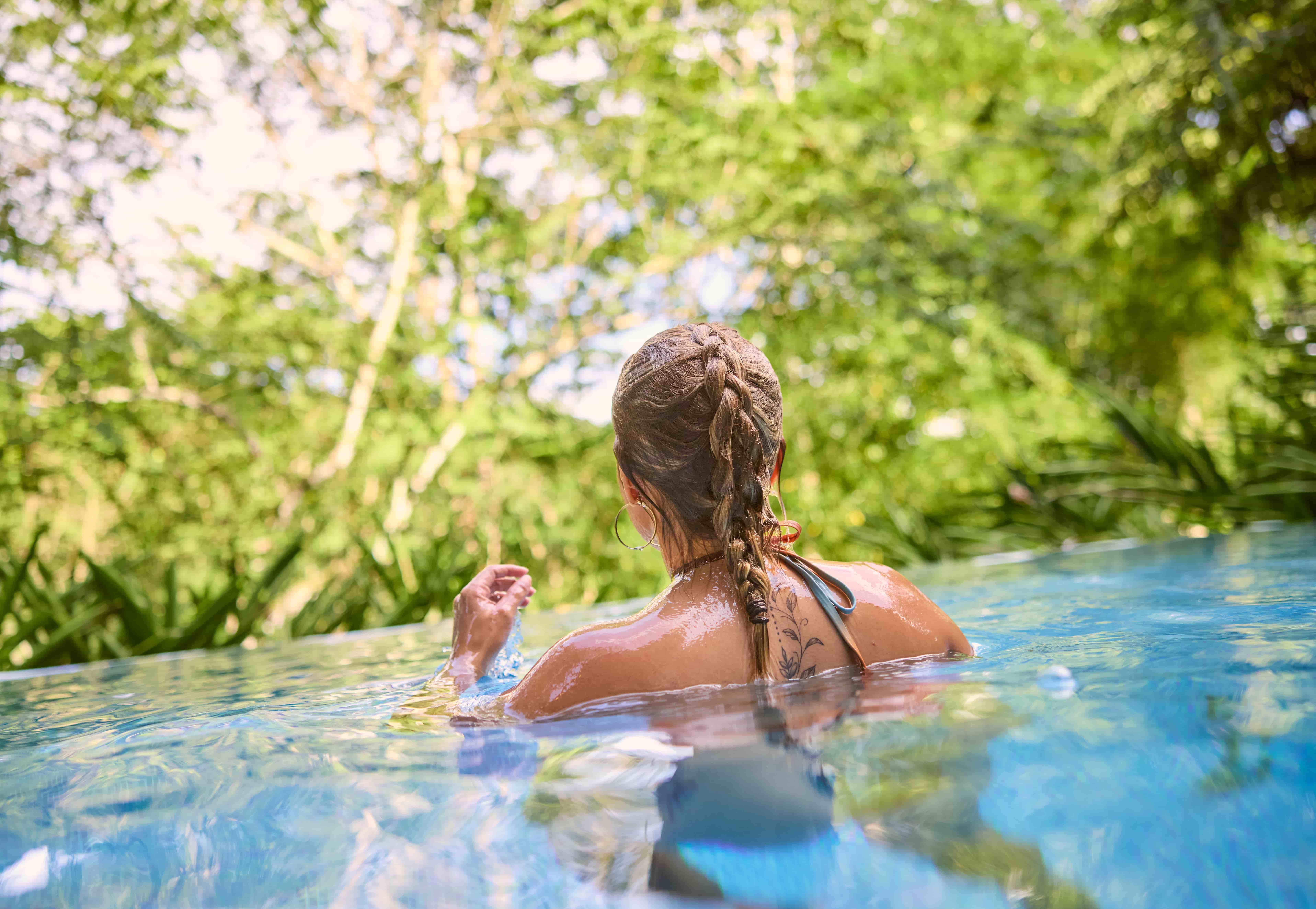 Woman relaxes in Chaa Creek villa infinity pool, Belize Woman relaxing in private villa infinity pool overlooking forest