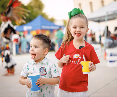 Young boy and girl enjoying slushies at a park event in Chandler, Arizona