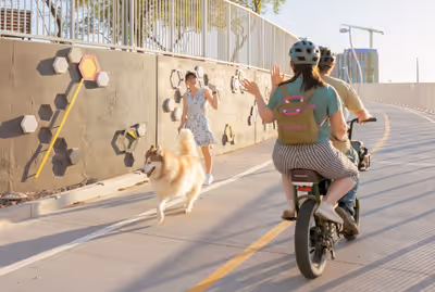 Couple on tandem bike waves to woman walking dog on bike path in Tempe, Arizona