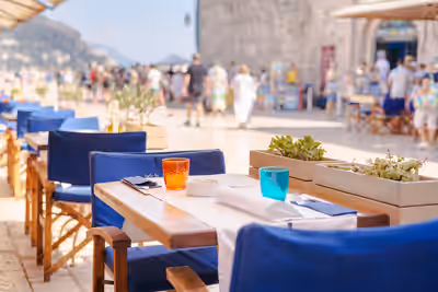 Outdoor café table set for dining with people walking in historic Dubrovnik