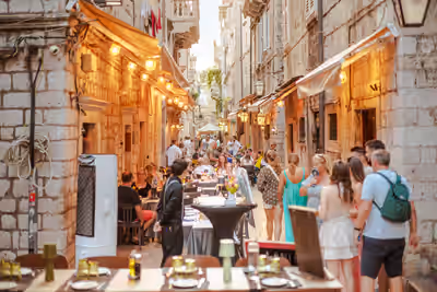 People dining outdoors on stone street at dusk in Old Town Dubrovnik, Croatia