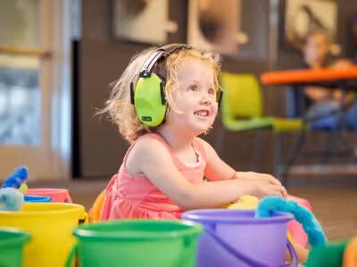 Young girl in hearing protection playing with sensory materials at a museum exhibit
