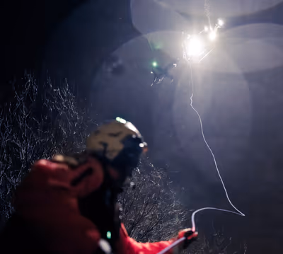 Bell 429 helicopter lowering hoist cable during nighttime rescue in Arizona desert rain