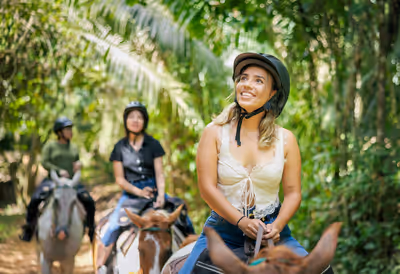 Women horseback riding through lush jungle trails near San Ignacio Belize