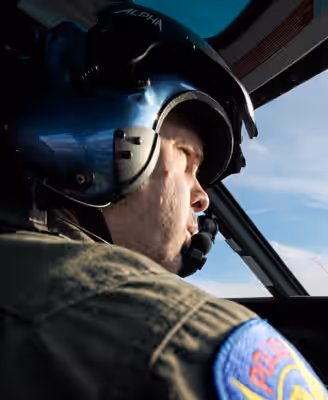 Close-up of police helicopter pilot wearing helmet and flight suit during patrol mission