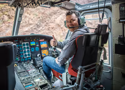 Smiling pilot in right seat of idling Bell 212 helicopter on the ground in Arizona