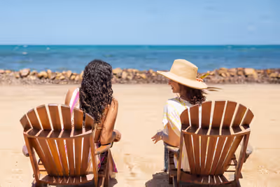 Two women sitting in beach chairs smiling at each other on the coast of Placencia Belize