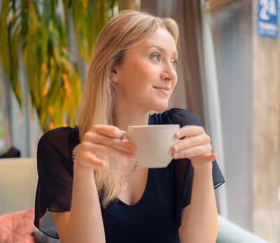 Young woman sipping coffee and looking out window at Tējo Tea House in Riga, Latvia