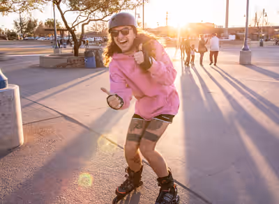 Rollerblader in pink hoodie skating through Tempe Beach Park at sunset in Arizona