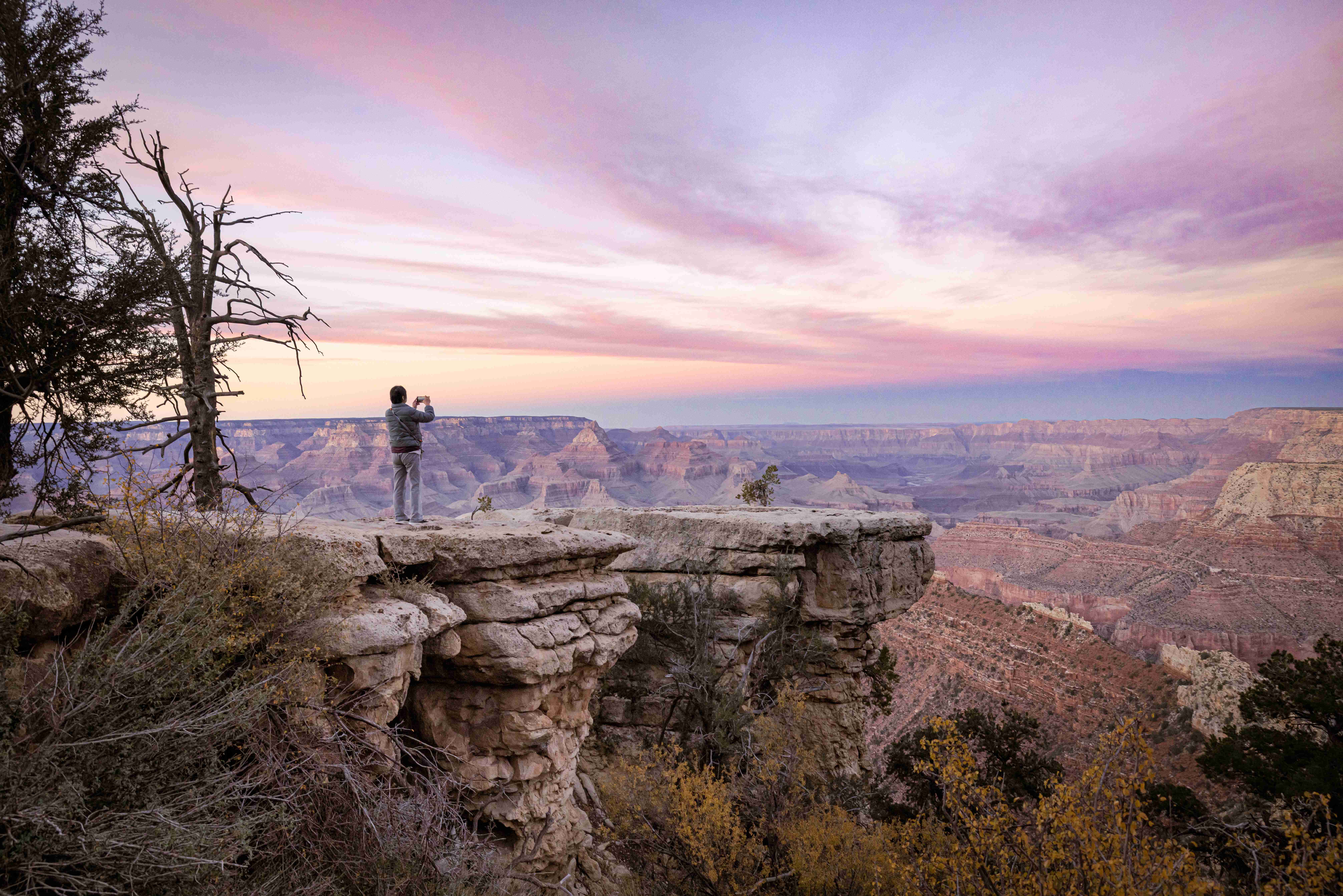 Tourist taking photo at Grand Canyon South Rim at dusk with colorful sky
