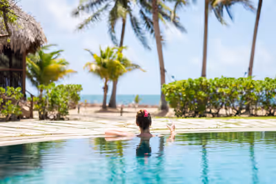 Woman relaxing in infinity pool with ocean view at a luxury resort in Placencia Belize