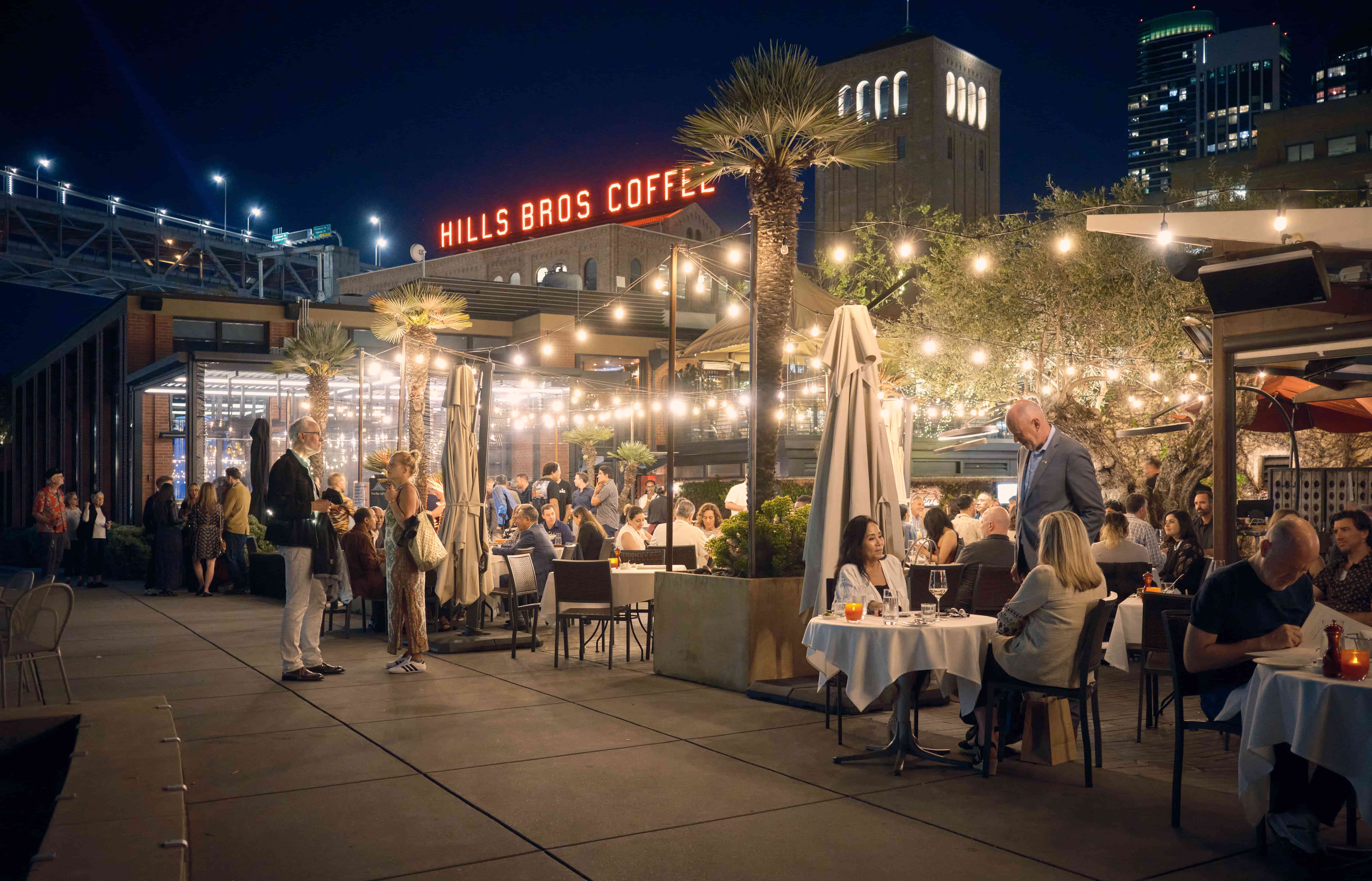 Outdoor evening dining on Waterbar patio with Hills Bros Coffee sign behind