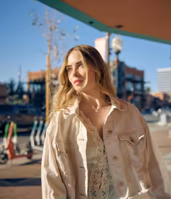 Young woman in cream denim jacket posing on Mill Avenue in downtown Tempe Arizona