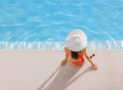 Overhead view of woman in sun hat sitting by luxury pool in Scottsdale