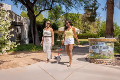 Two women walking a small dog and laughing in the Maple Ash neighborhood of Tempe, Arizona